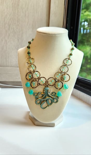 A unique Octopus necklace surrounded by hammered rings a green glass