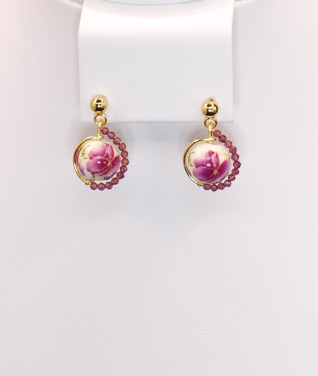 An asymmetrical design featuring a lovely porcelain bead in the center and Garnet accents