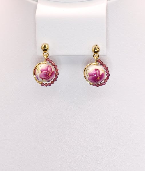 An asymmetrical design featuring a lovely porcelain bead in the center and Garnet accents