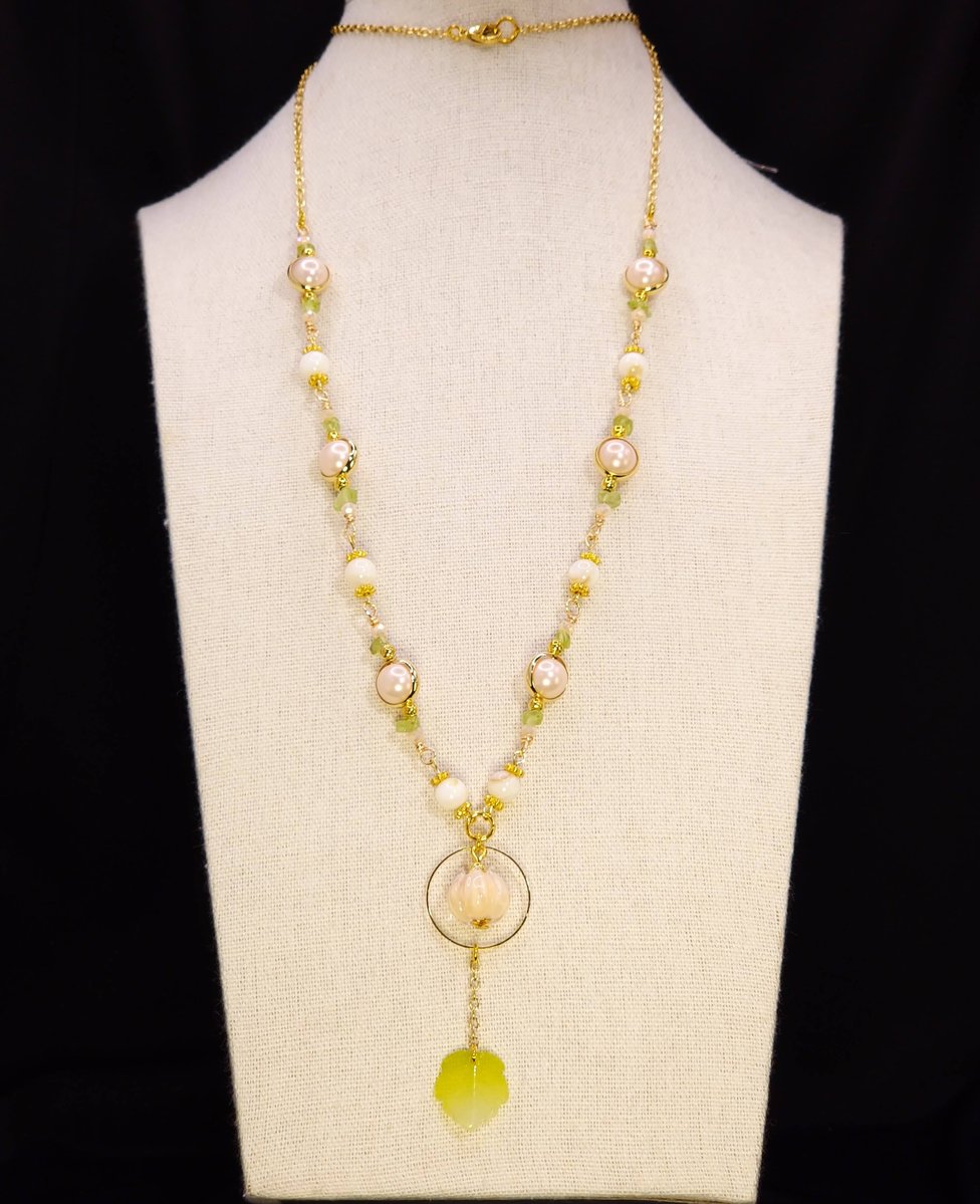 A long gold chain featuring a glass lamp work focal and man made pink pearls