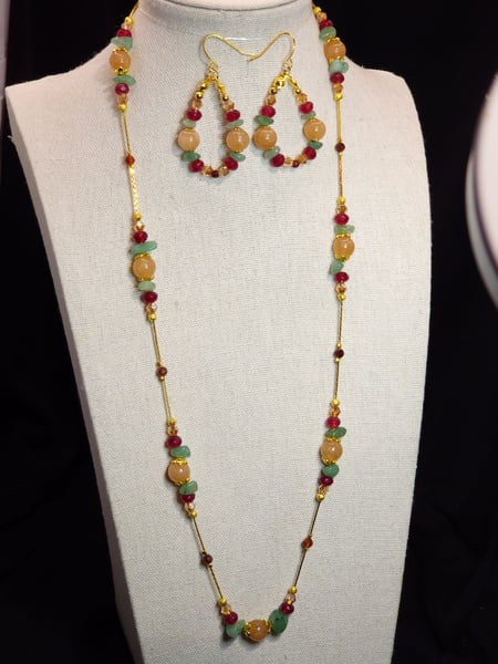 A gold chain featuring peach quartz, garnet, aquamarine and glass rondelles